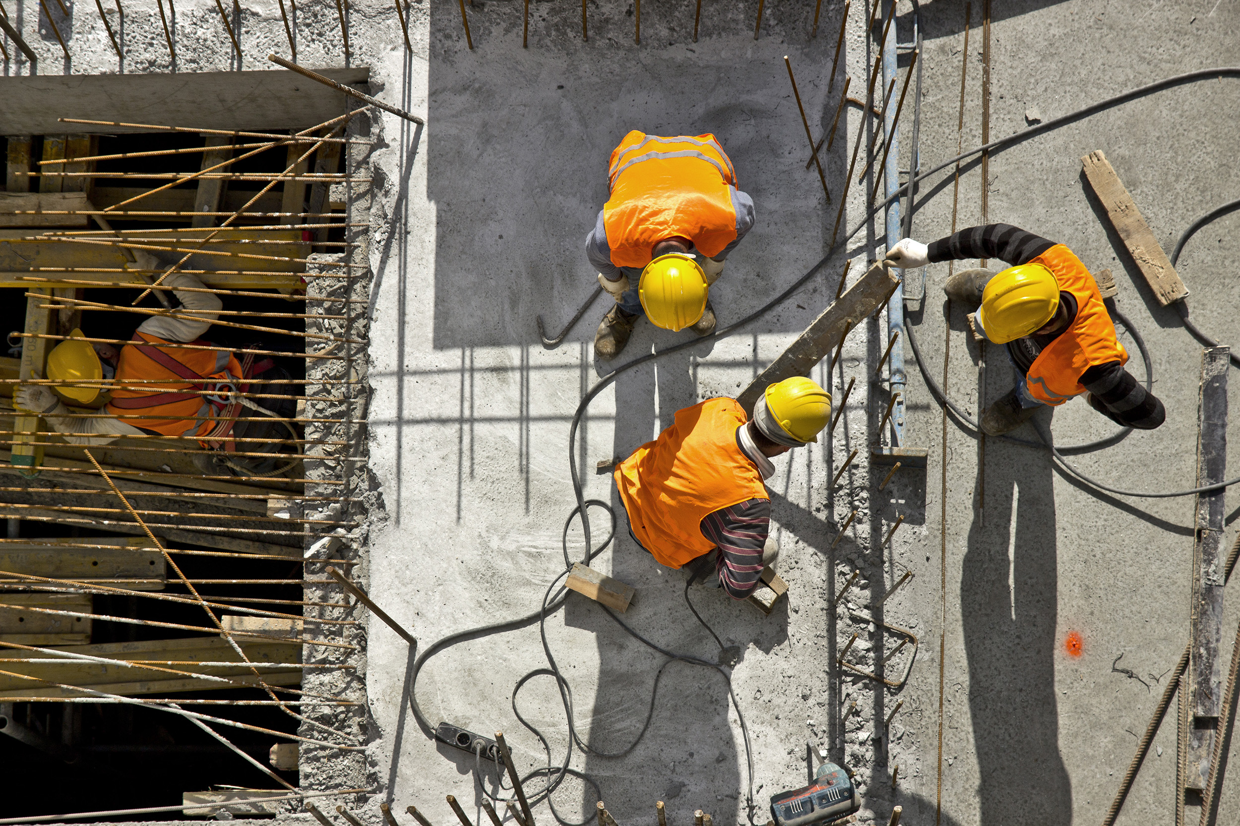 Three construction worker on a job site with rebar and concrete.