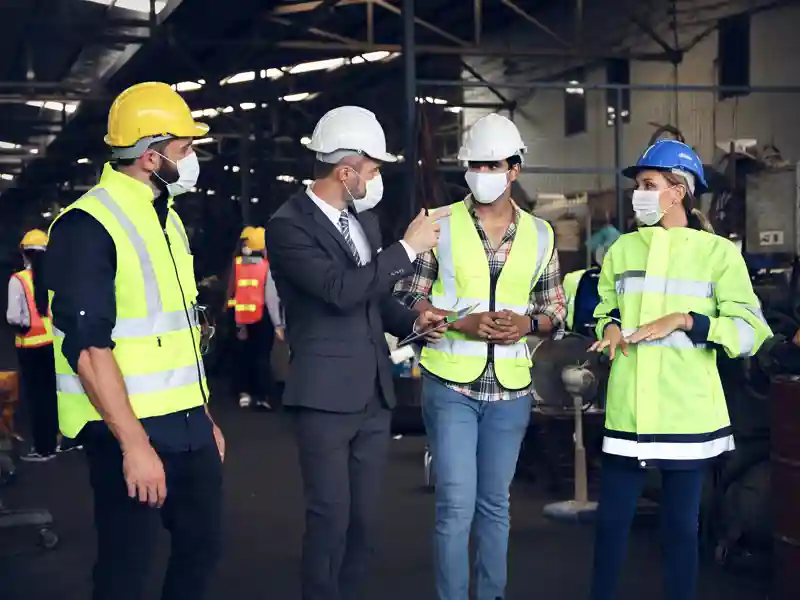Three construction worker do a walk-thru with a person in a suit.